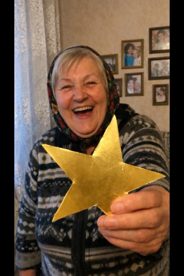 A grandmother laughing and holding up a paper star
